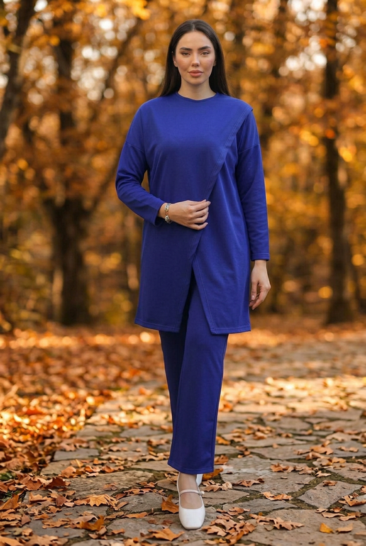 Model with one hand on her belly wearing the blue set against an autumn background